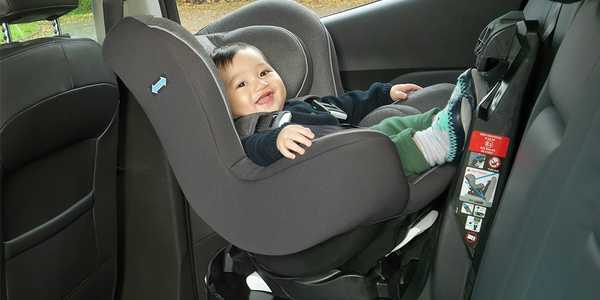 A baby sitting in a Cuggl Owl Spin group 0+/1 ISOFIX car seat.